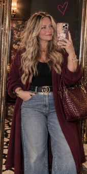 Jennifer in a burgundy coat and jeans, taking a mirror photo